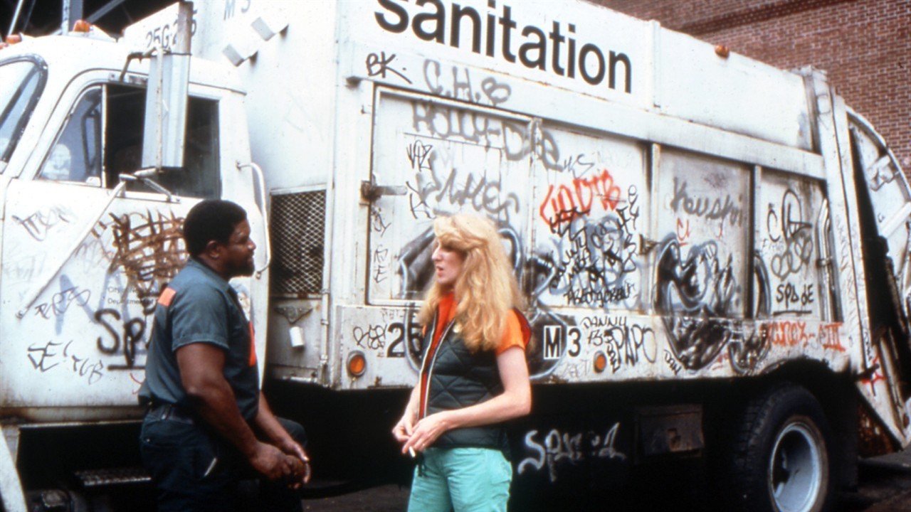 People in front of a graffitied garbage truck